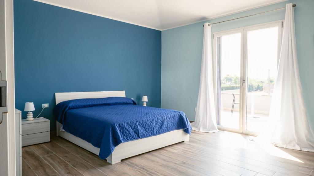 a blue bedroom with a bed and a window at Tenuta Papola B&b in Brindisi