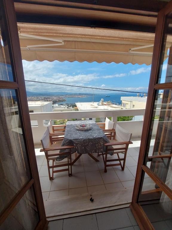 a table and chairs on a balcony with a view of the ocean at Eolia apartment with panoramic Chania view in Chania Town