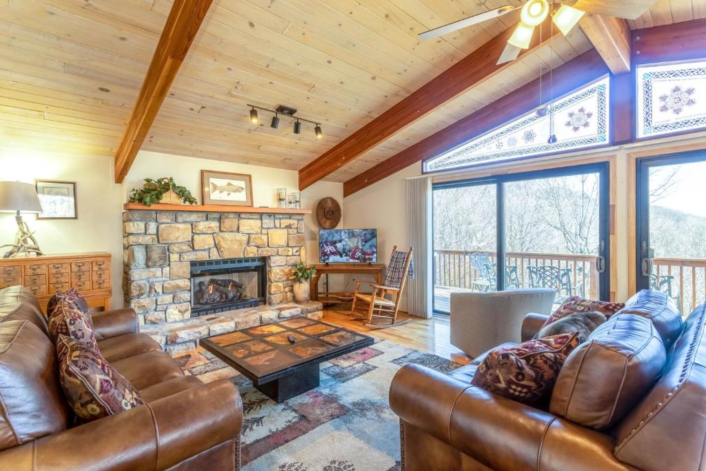 a living room with leather furniture and a stone fireplace at Heavens Door in Beech Mountain