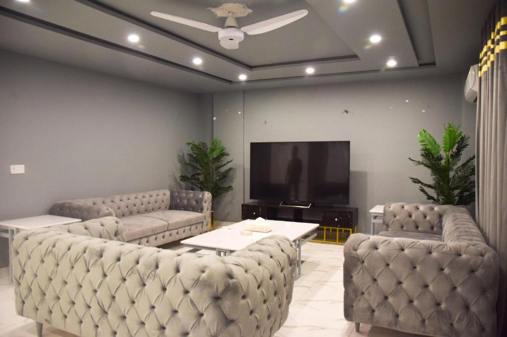 una sala de espera con sofás y TV de pantalla plana. en Luxe Suites Bahria Town Lahore en Lahore