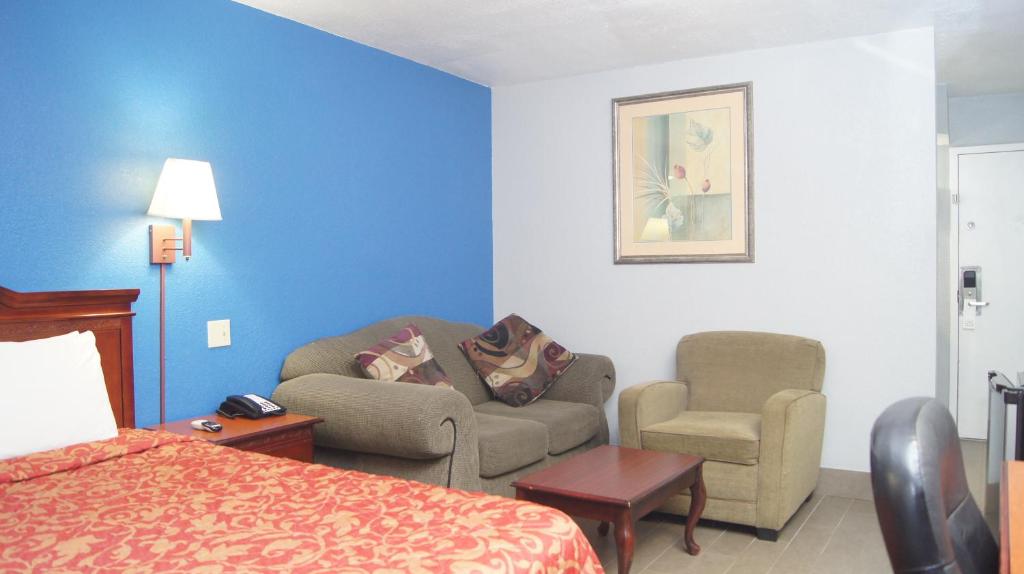 a hotel room with a bed and a couch and a chair at Holiday Lodge & Suites in McAlester