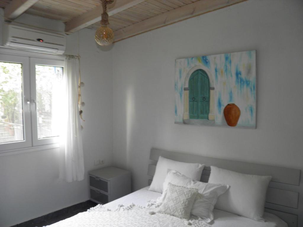 a white bedroom with a bed and a window at hantra thalasia 1 in Poros