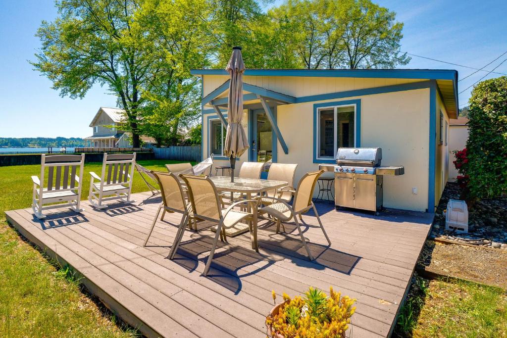 eine Terrasse mit einem Tisch, Stühlen und einem Grill in der Unterkunft Waterfront Hood Canal Cottage Steps to the Beach! in Belfair