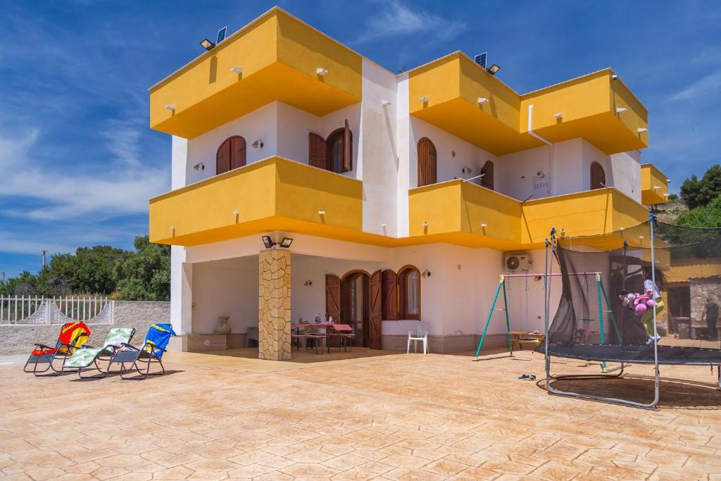 um edifício amarelo e branco com cadeiras em frente em Matisé Home Relax em Sciacca