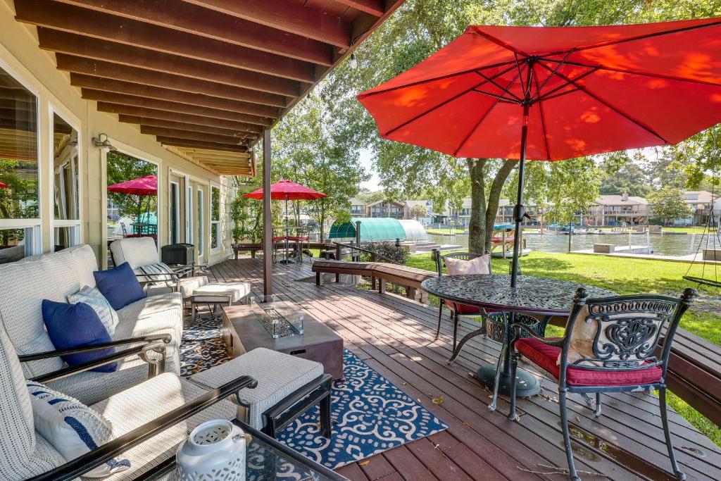 eine Terrasse mit einem Tisch und einem roten Regenschirm in der Unterkunft Lakefront Montgomery Home with Porch and Dock! in Montgomery