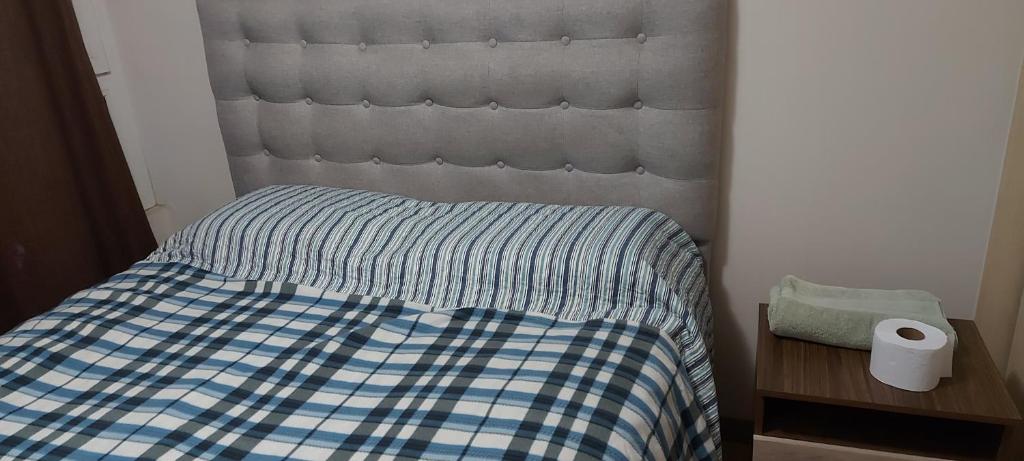 a bed with a blue and white checkered comforter and a roll at habitacion Depto Business in Santiago