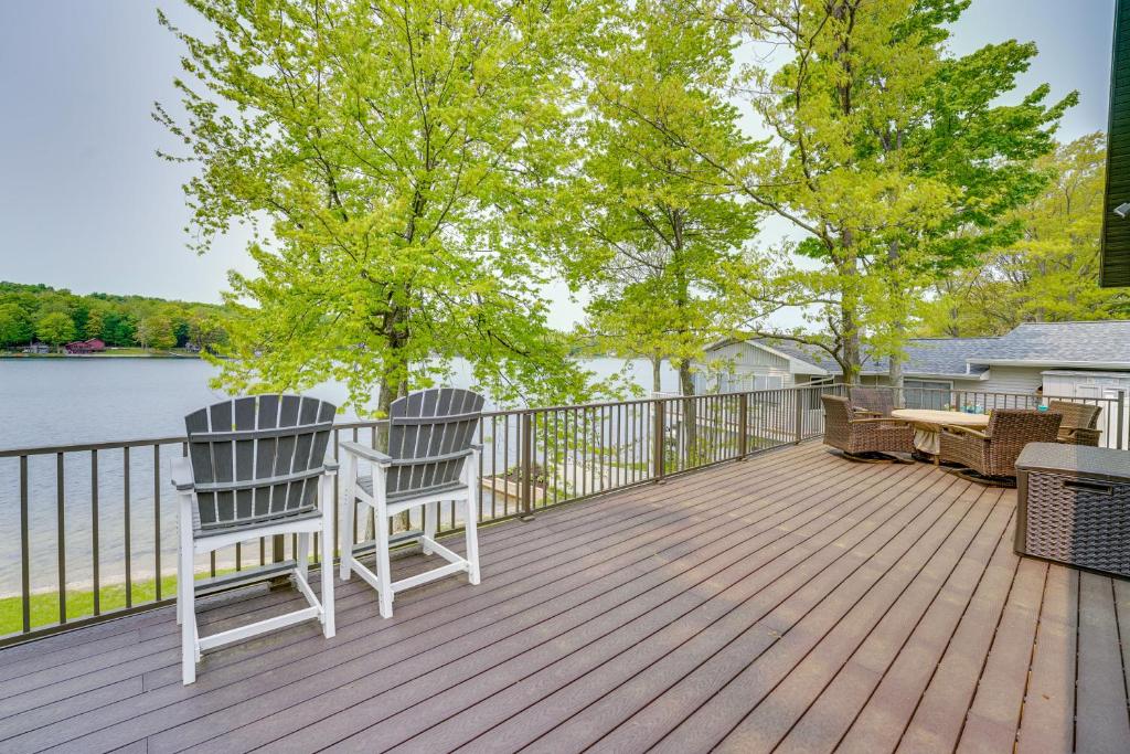 two chairs sitting on a deck overlooking a lake at Family Home on Crystal Lake with Private Beach! in Hart