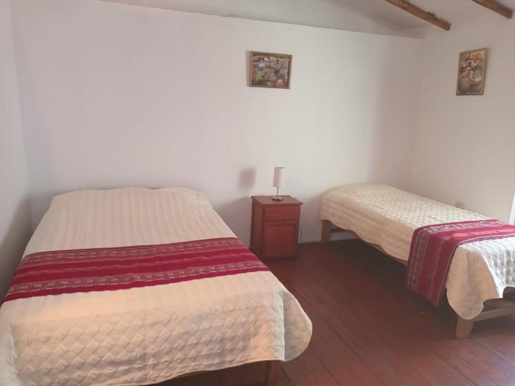 a bedroom with two beds and a night stand with a bedskirts at Posada Del Valle Lodge in Urubamba