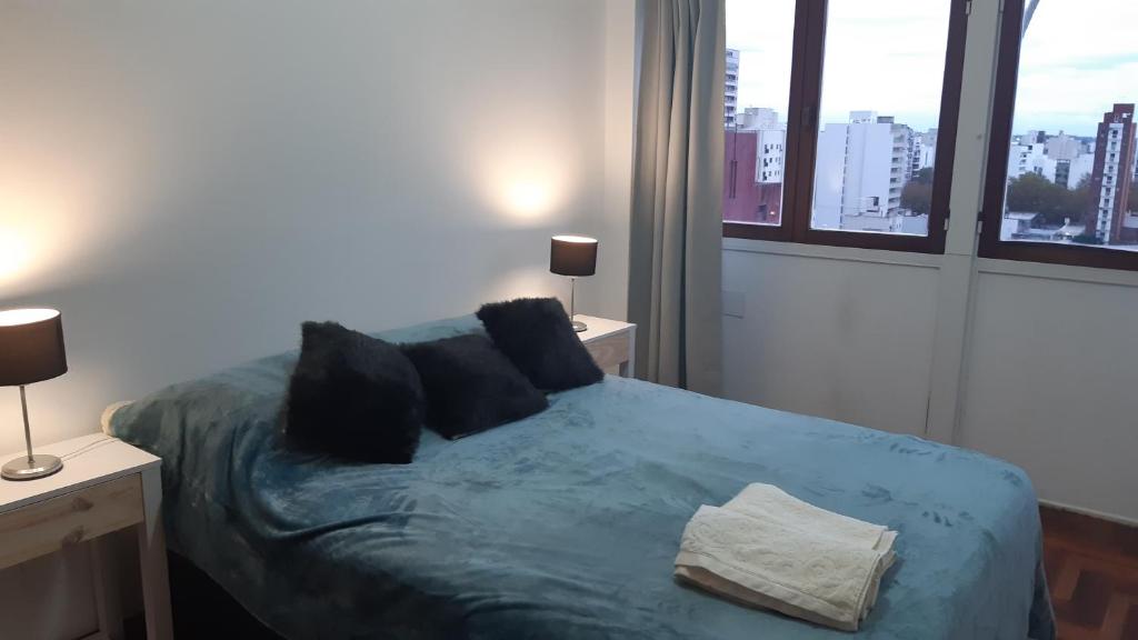 1 Schlafzimmer mit einem Bett mit blauer Bettwäsche und 2 Fenstern in der Unterkunft 9y45 in La Plata