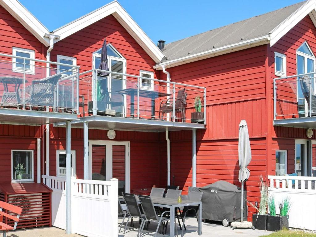 uma casa vermelha com uma mesa e cadeiras em frente em Two-Bedroom Holiday home in Hadsund 11 em Nørre Hurup