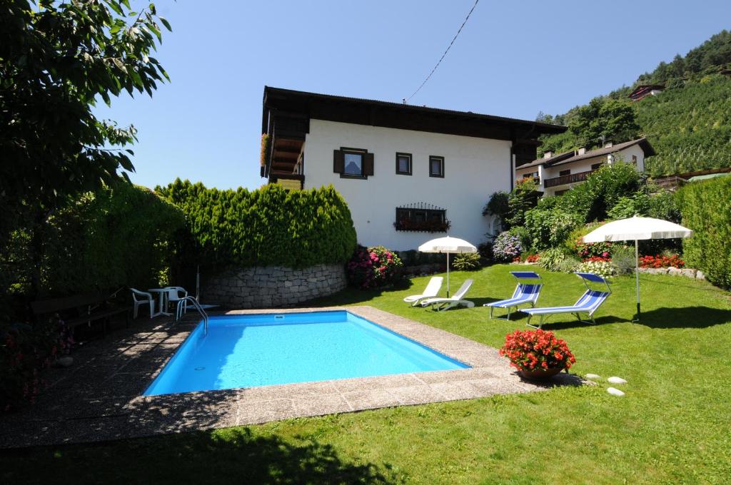 a swimming pool in a yard with chairs and umbrellas at Appartments Innerhofer in Rifiano