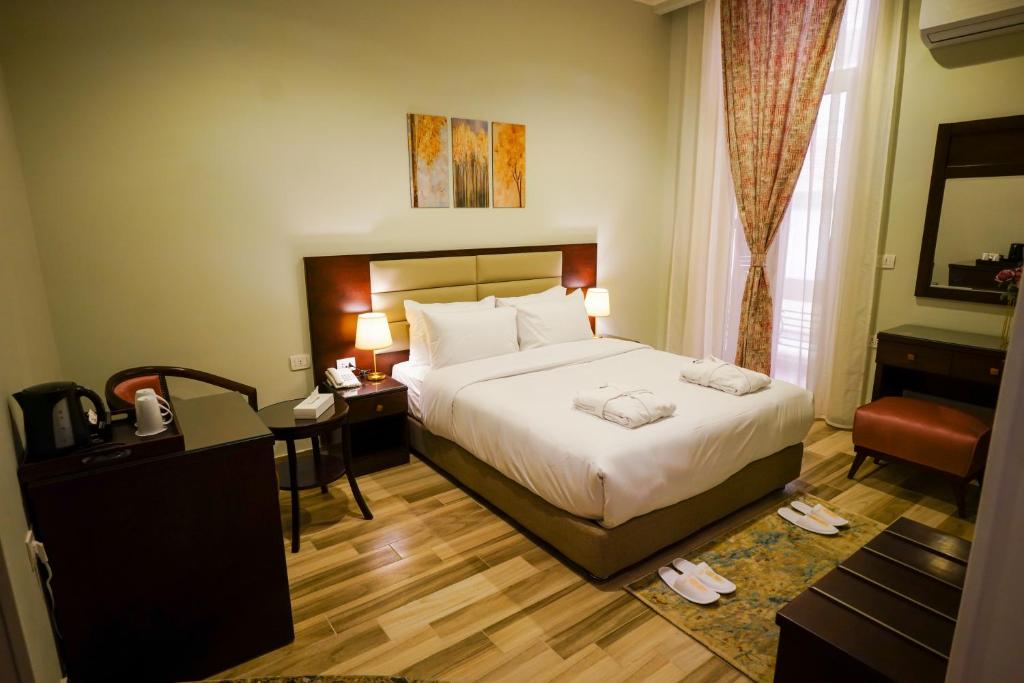 a hotel room with a bed and a desk and a chair at Savoy Hotel ELMinya in Al Minya