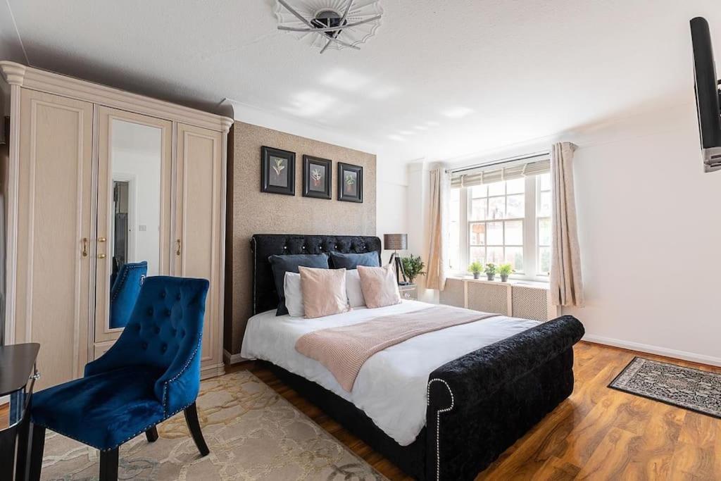 - une chambre avec un grand lit et une chaise bleue dans l'établissement Beautiful Two Bedroom Apartment Nearby Hyde Park, à Londres