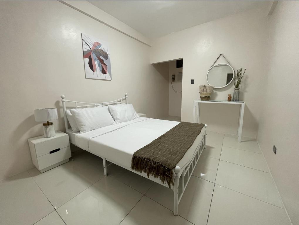 a white bedroom with a bed and a mirror at Cresta Dormitory in Dumaguete