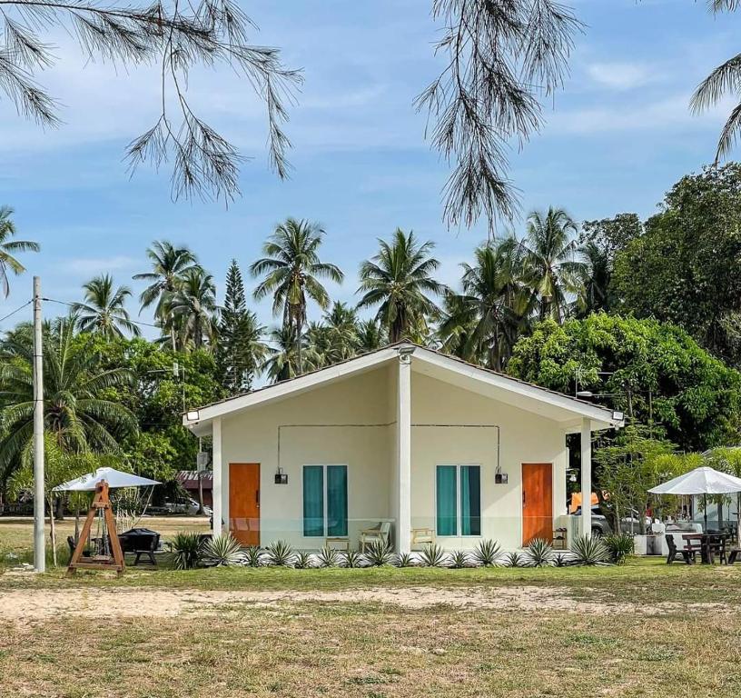 a small white house with palm trees in the background at DamaiiKu in Cherating