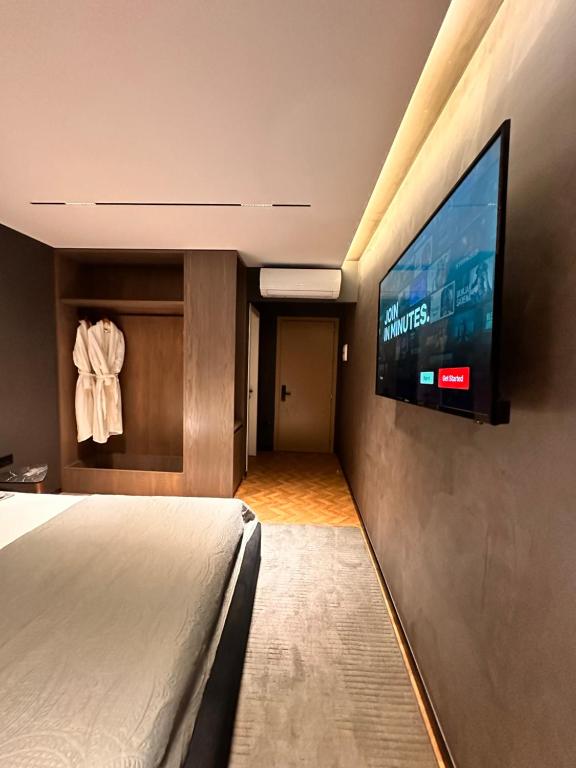 a hotel room with a bed and a flat screen tv at AGATE HOTEL self check in in Tirana