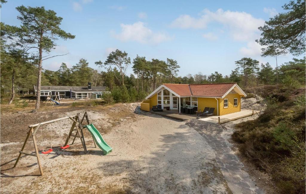 a yellow house with a playground in front of it at Cozy Home In Nex With Sauna in Vester Sømarken