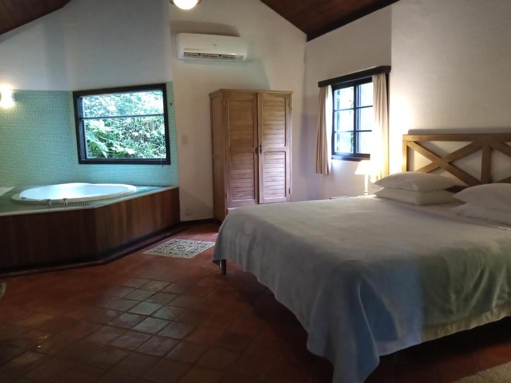 um quarto com uma cama e uma banheira em Canto do Bosque - Chalé Sabiá com hidromassagem em Araras Petropolis