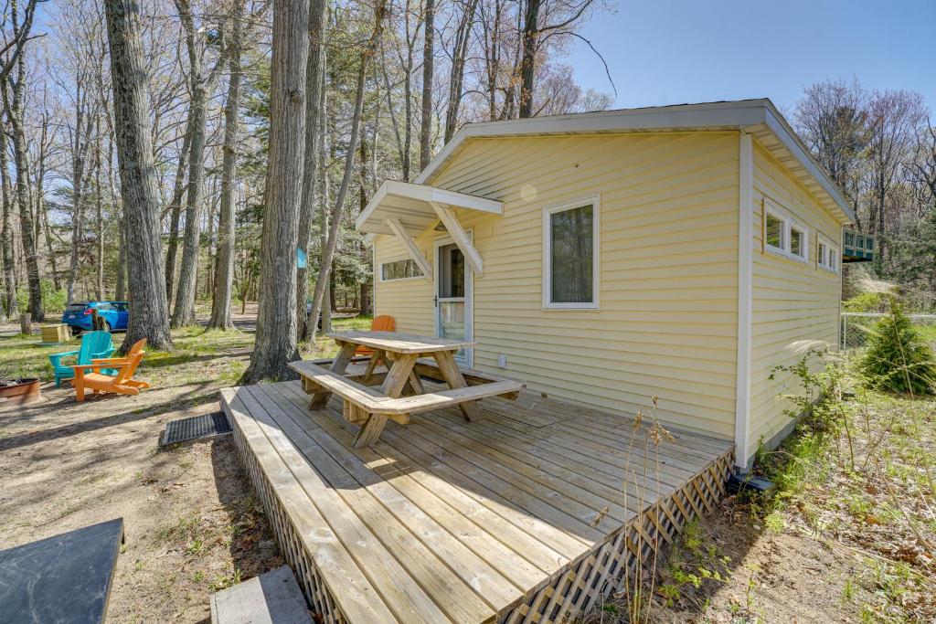 Cabaña amarilla pequeña con mesa de picnic en una terraza de madera en 4-Season Gold Coast Cottage, 2 Mi to Winter Sports, en Muskegon