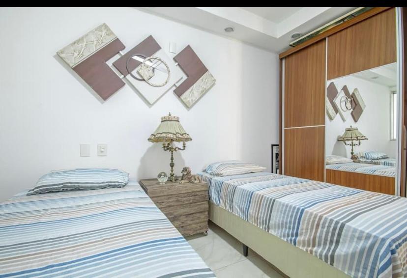een slaapkamer met 2 bedden en een spiegel bij Paraíso a beira-mar na praia de Búzios/RN in Nísia Floresta