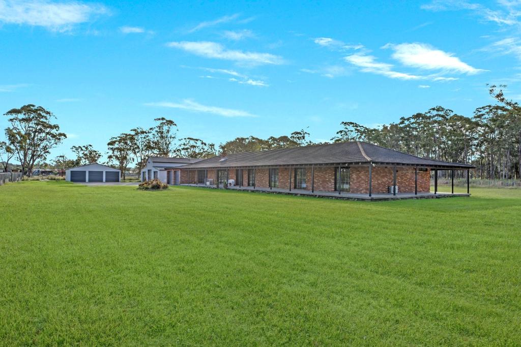 um edifício de tijolos com um campo de relva em frente em The Weltara - 6 bedrooms House Near Anna Bay em Williamtown