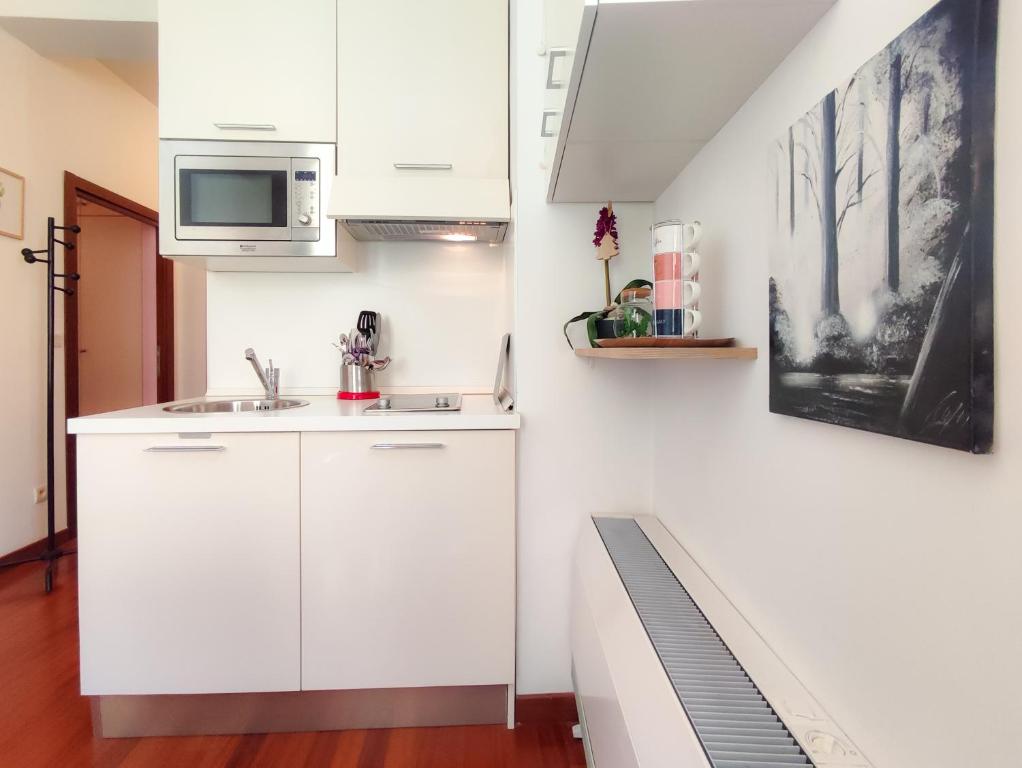 eine weiße Küche mit einer Spüle und einer Mikrowelle in der Unterkunft Grimaldi Centrale 5 Pers Wi-Fi AC in Nizza