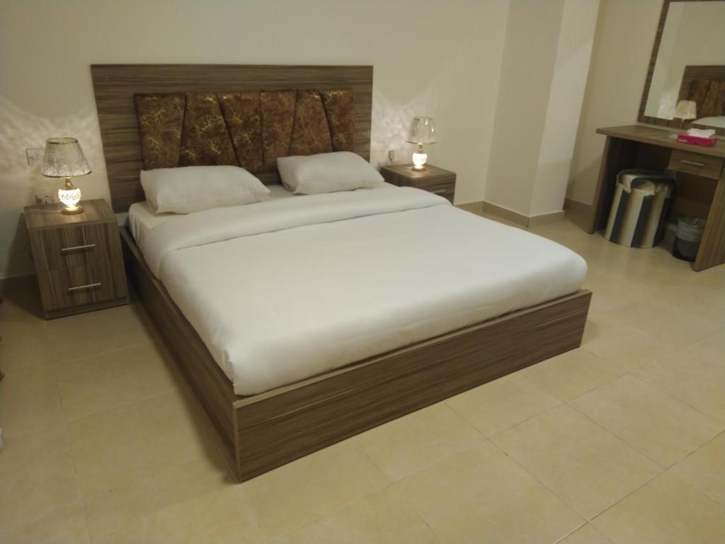 1 cama grande en una habitación con 2 mesitas de noche en Rayan Hotel Suites en Amán