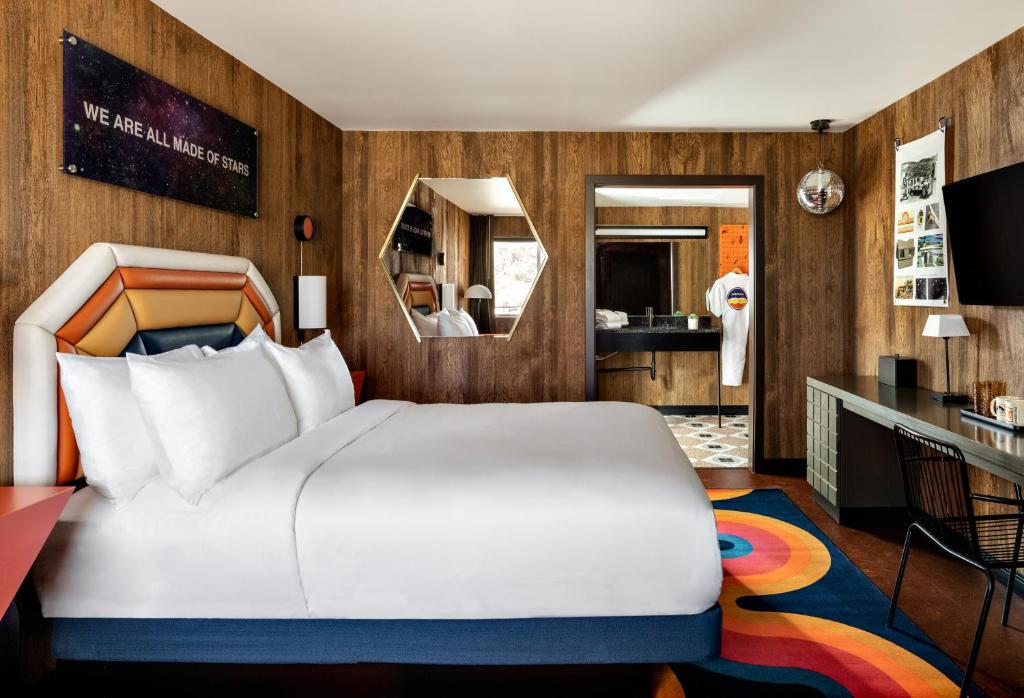 a bedroom with a large white bed and a bathroom at Americana Motor Hotel in Flagstaff