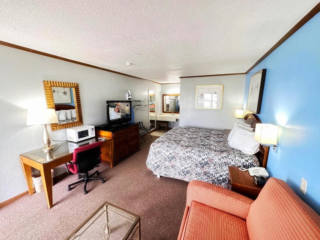 a hotel room with a bed and a desk and a television at Night Inn in Sweet Springs