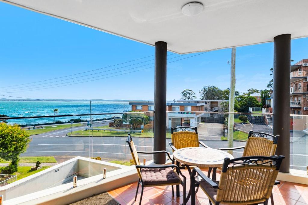 a balcony with a table and chairs and a view of the ocean at Bayview Towers in Nelson Bay