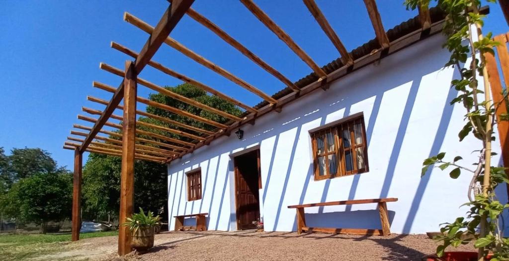 une maison blanche avec une pergola en bois dans l'établissement Angiru, à Mercedes