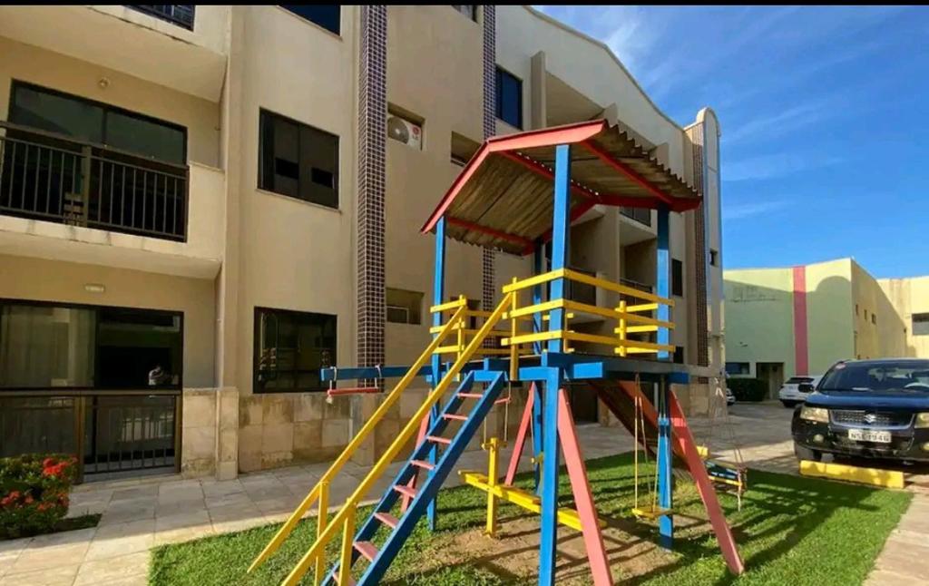 um parque infantil com um escorrega em frente a um edifício em Crystal Park Flat em Aquiraz