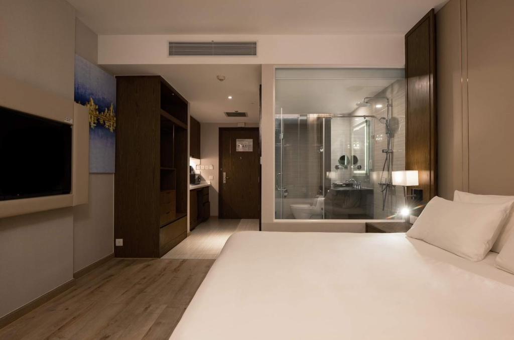 a bedroom with a large white bed and a television at Panorama Apartment Nha Trang in Nha Trang