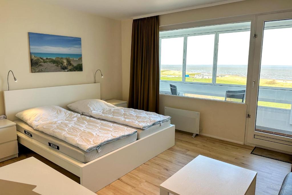 a bedroom with a bed and a large window at Haus "Atlantic" Appartement ATL 604B in Cuxhaven