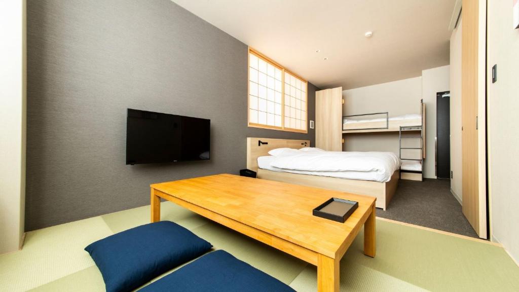um pequeno quarto com uma cama, uma mesa e uma televisão em ALPHABED INN Fukuoka Ohori Park em Fukuoka