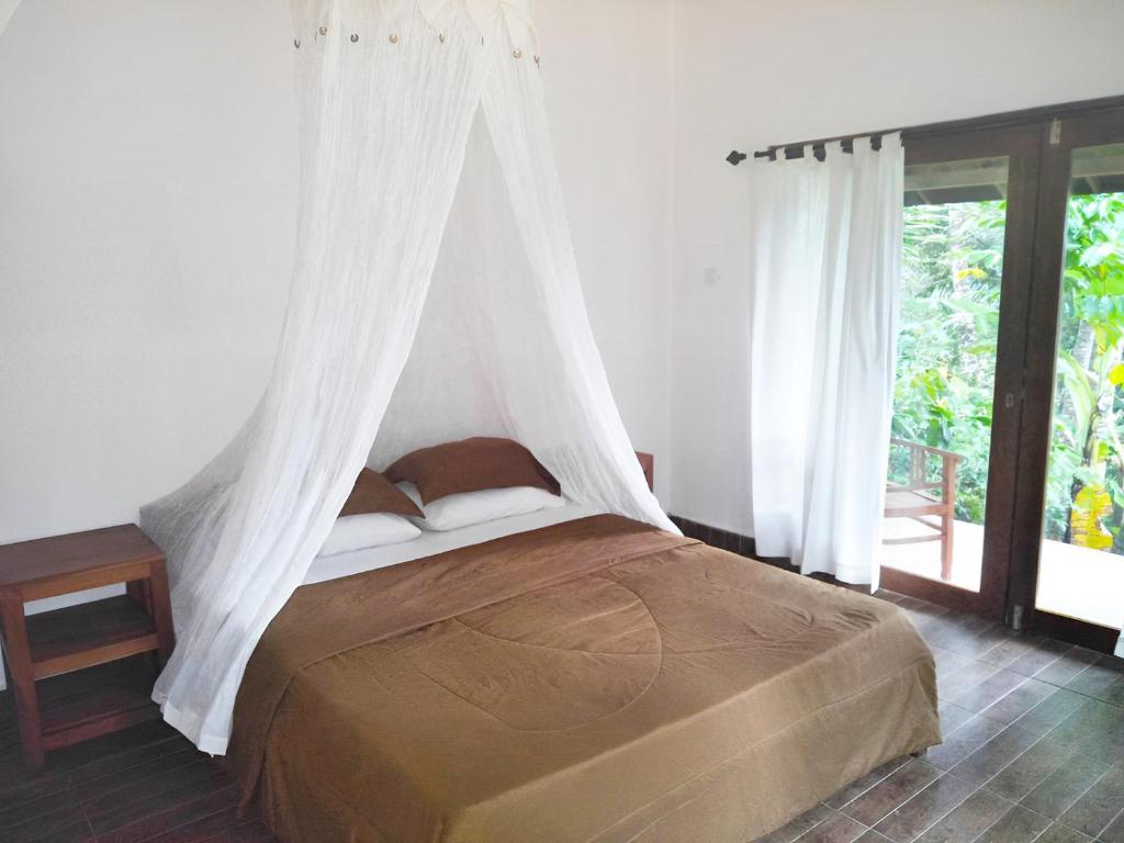 a bedroom with a bed with a mosquito net at Purana Guest House in Tabanan