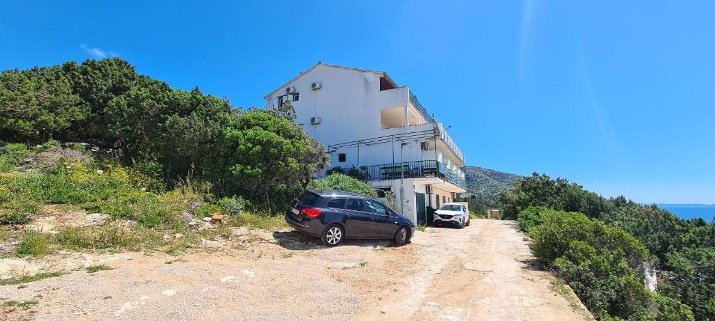 a car parked in front of a building on a dirt road at Apartments Ana i Ante Punta in Milna