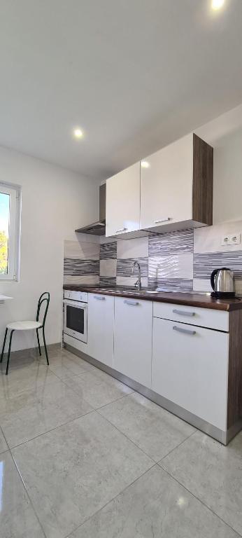 a kitchen with white cabinets and a table and a chair at Apartments Ana i Ante Punta in Milna