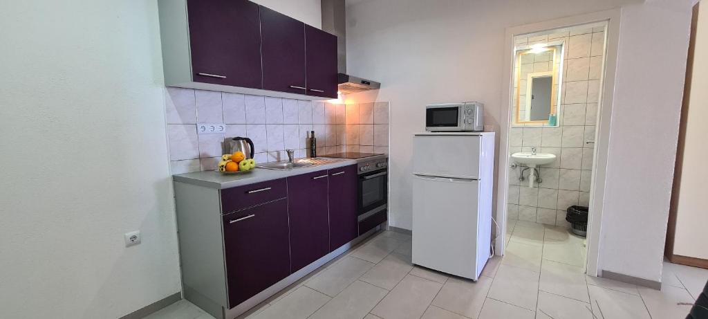 a kitchen with purple cabinets and a white refrigerator at Apartments Ana i Ante Punta in Milna