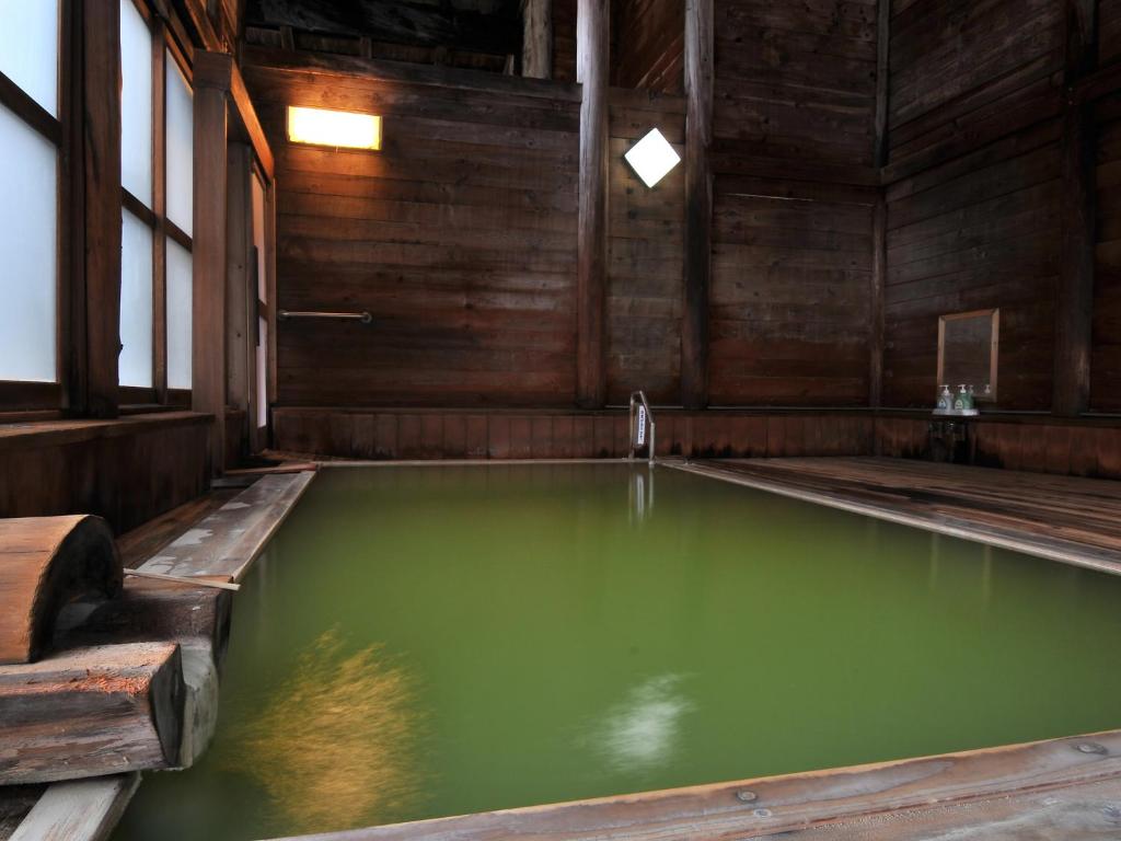 una gran piscina de agua verde en un edificio de madera en Kumanoyu Hotel, en Yamanouchi