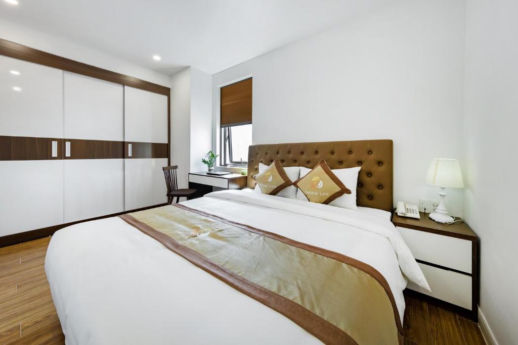 een slaapkamer met een groot wit bed en een bureau bij Phong Lan Apartments in Hai Phong