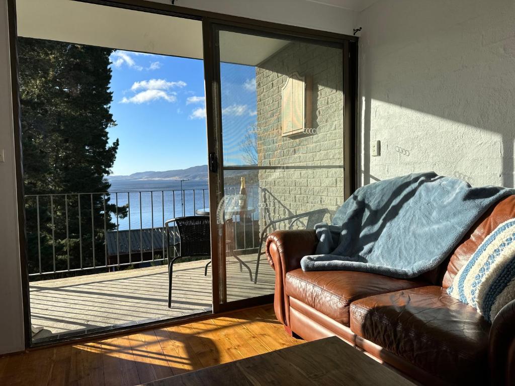 a living room with a couch and a view of a balcony at Jindabyne Lake View in Jindabyne