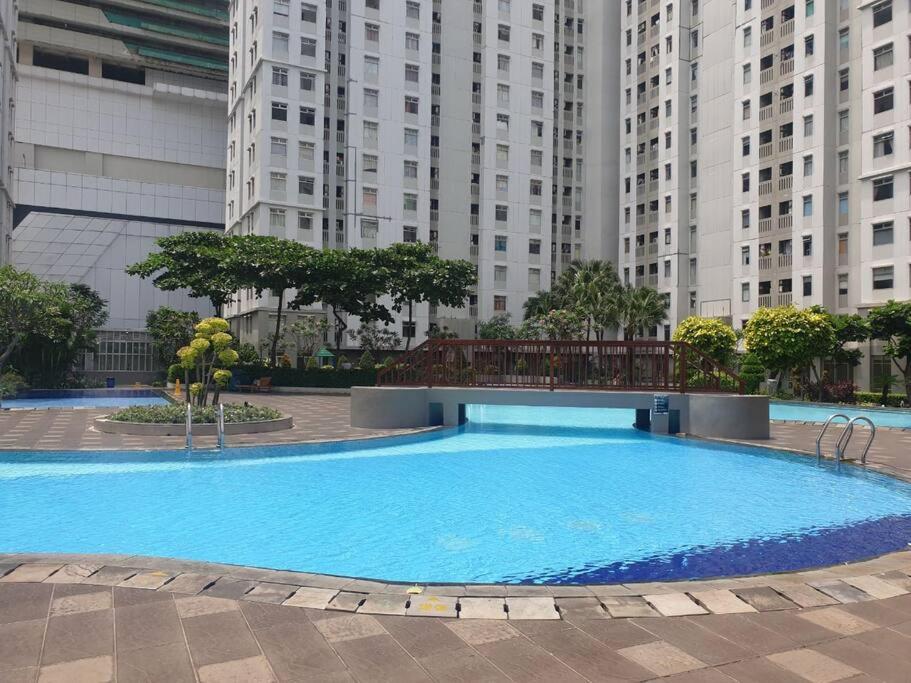 雅加達的住宿－Apartemen 1 BR Studio Baywalk Pluit Cozy Aesthetic North Jakarta，一座位于城市的游泳池,有高大的建筑