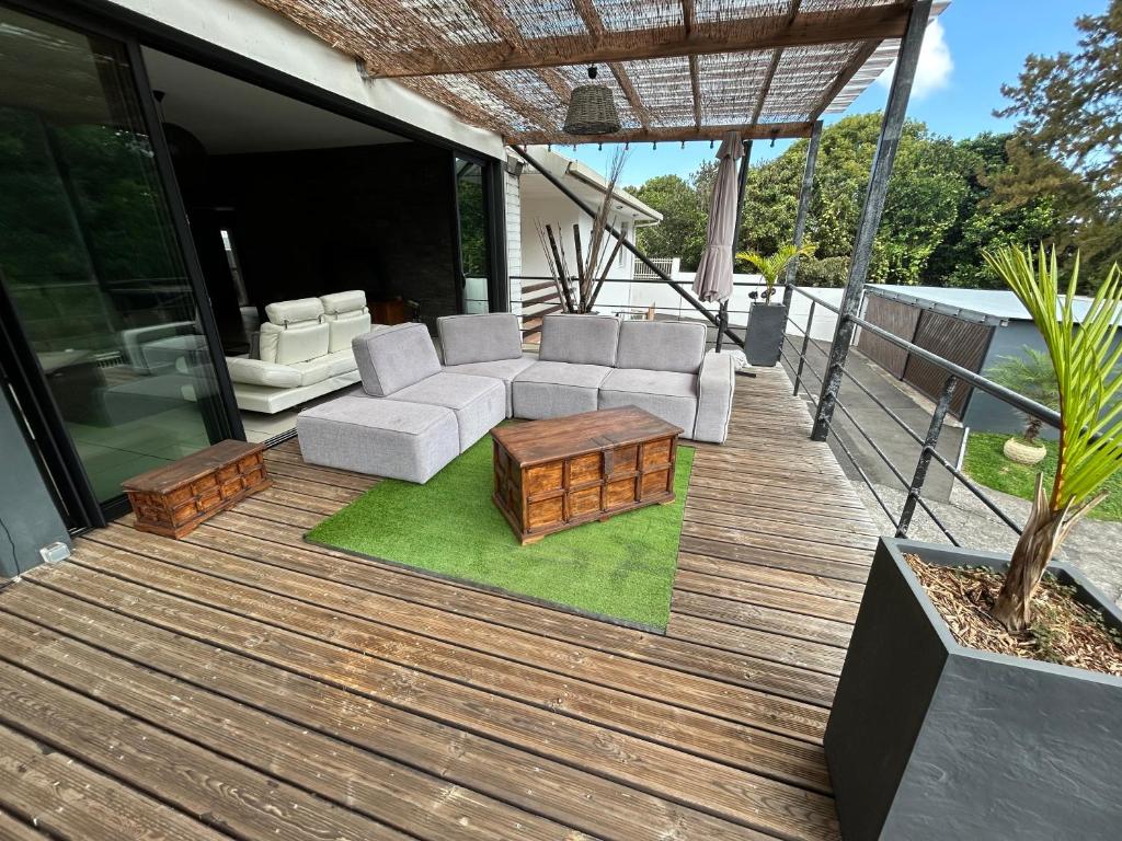 una terrazza in legno con divano e tavolino da caffè di MEGA APPARTEMENT a Le Tampon