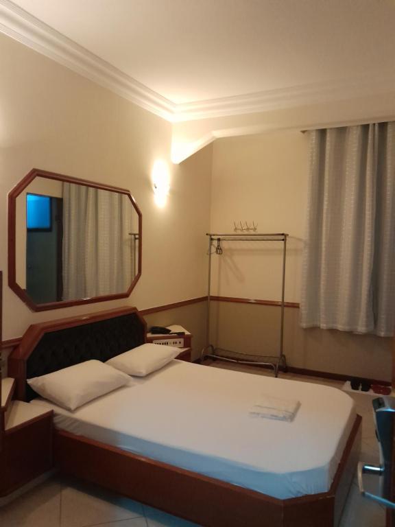 a small bedroom with a bed and a mirror at Hotel Paris in São Paulo