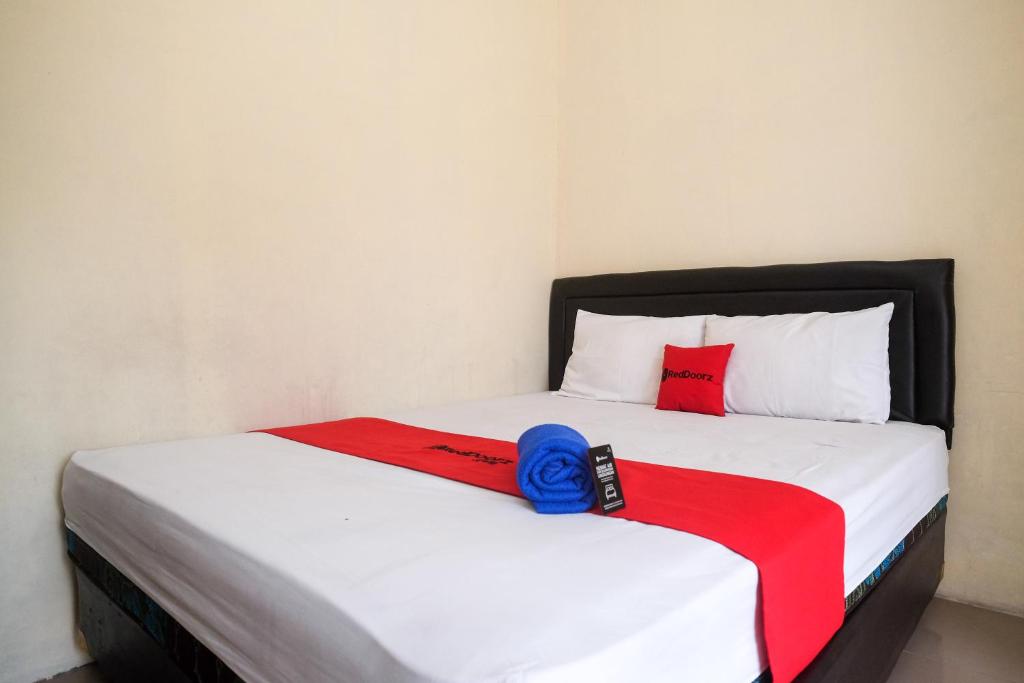 uma cama com um cobertor vermelho e azul em RedDoorz at Putri Syariah Brebes 