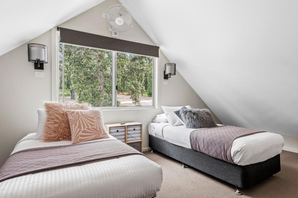 1 dormitorio en el ático con 2 camas y ventana en The Leaning Oak Holiday Lifestyles - Lake Conjola, en Conjola