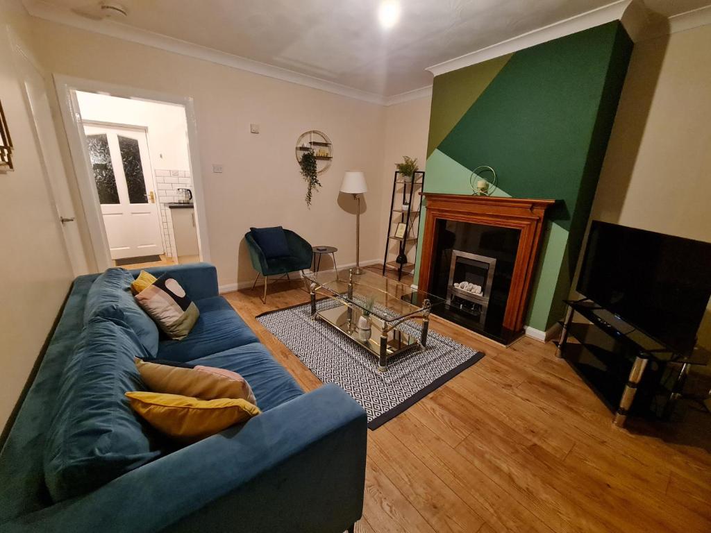 a living room with a blue couch and a fireplace at The Grove House with Free Parking in Hull