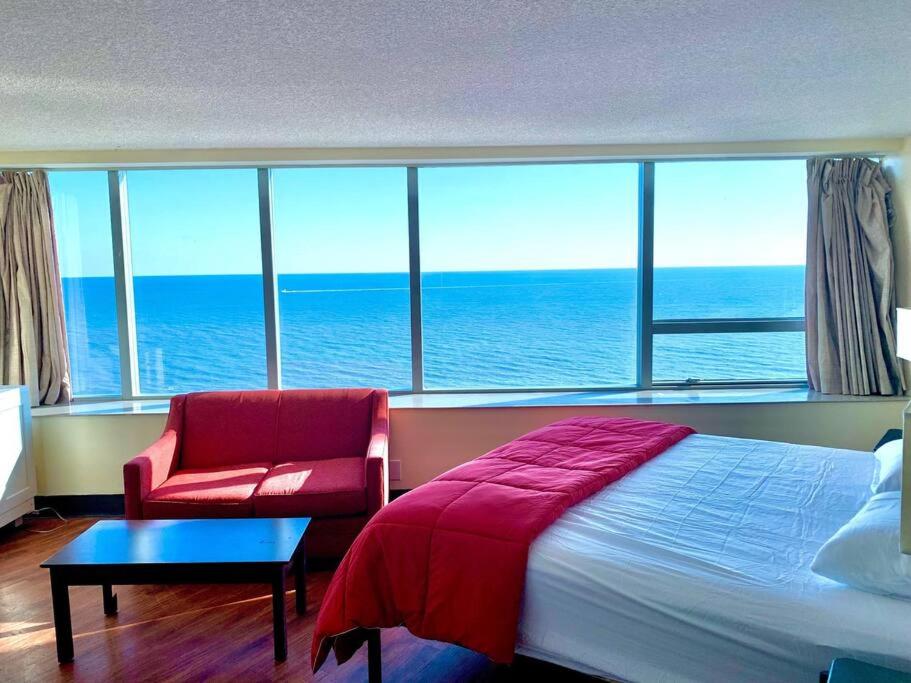 a bedroom with a bed and a chair and the ocean at Atlantic Palace Beachfront Ocean View in Atlantic City
