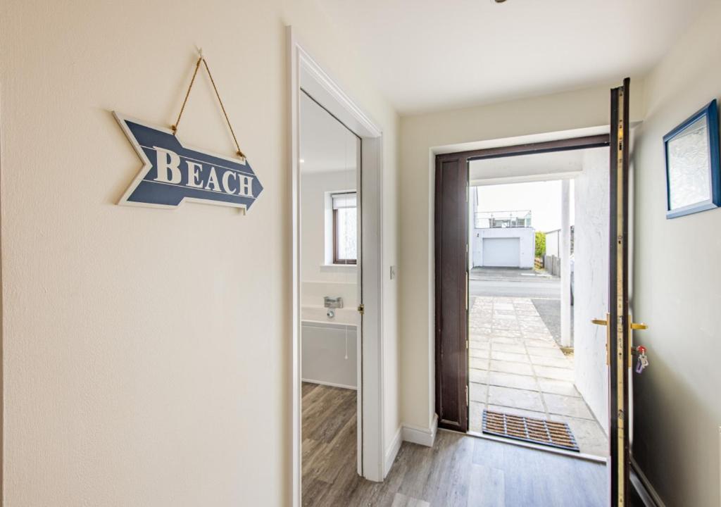 a door to a hallway with a beach sign on the wall at Annalie in Abersoch